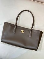 Dark taupe-brown leather tote bag with gold Chanel logo center, double top handles