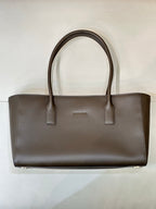 Structured taupe-brown leather tote bag with double handles and small strap pocket detail