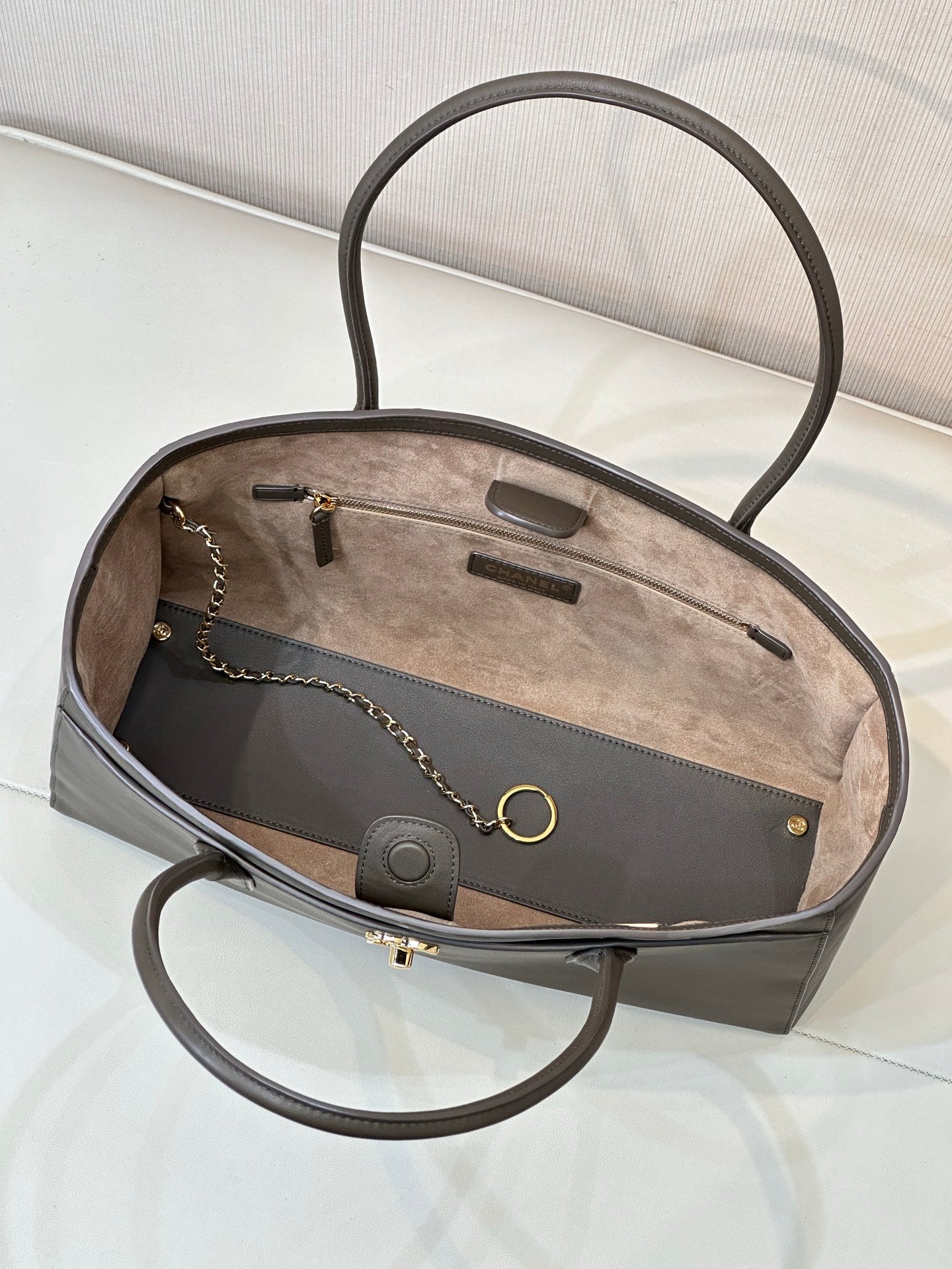 Brown leather tote bag open view with fabric lining, interior pockets, chain and ring