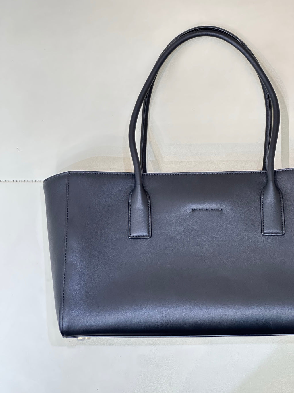 Navy leather tote bag front view with two handle straps and subtle center detail