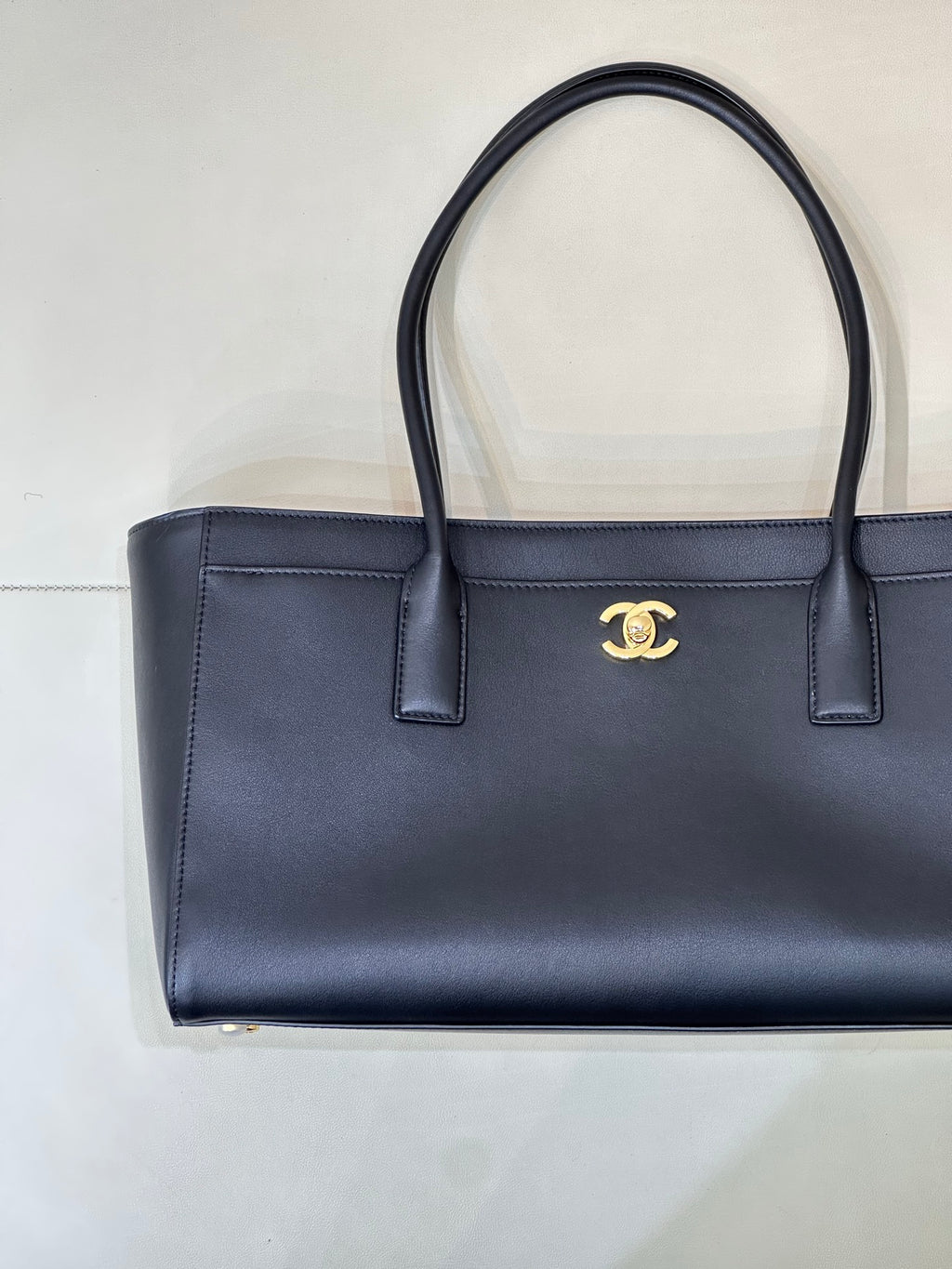 Navy leather tote bag with gold CC logo, structured front and two top handles