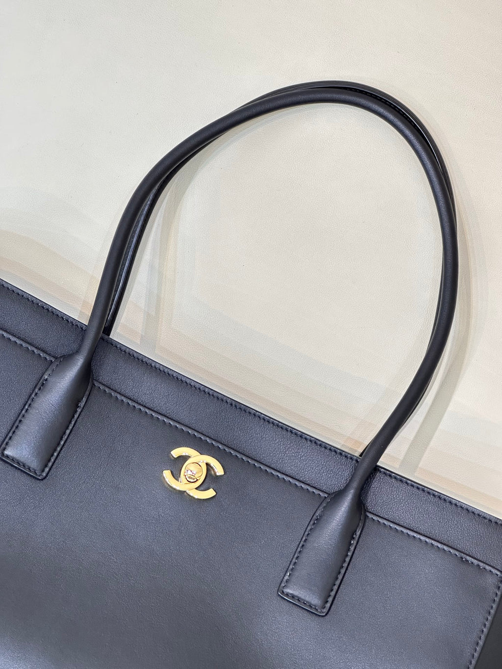 Navy leather tote bag front with gold CC logo and two short handle tabs