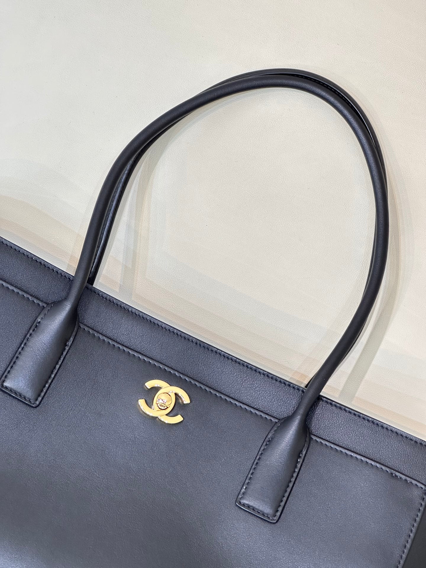 Navy leather tote bag front with gold CC logo and two short handle tabs