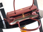 Burgundy Chanel handbag open with gold zipper, inner lining, and top handles