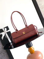 Burgundy Chanel handbag with top handles, front flap, and gold CC clasp