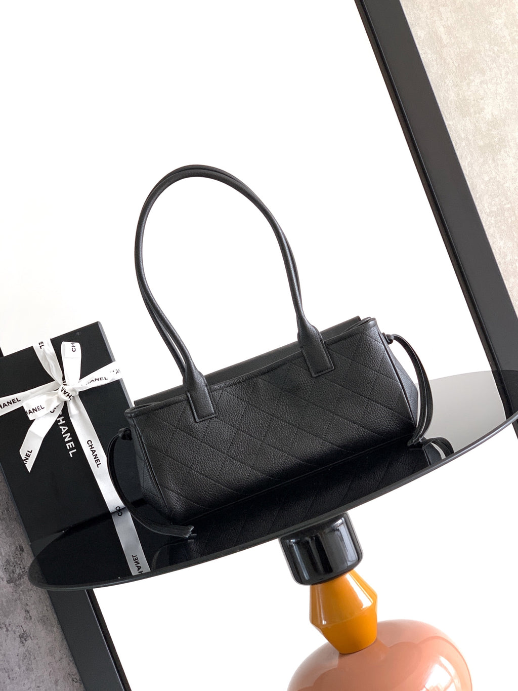 Black quilted leather handbag on side view with curved top handles