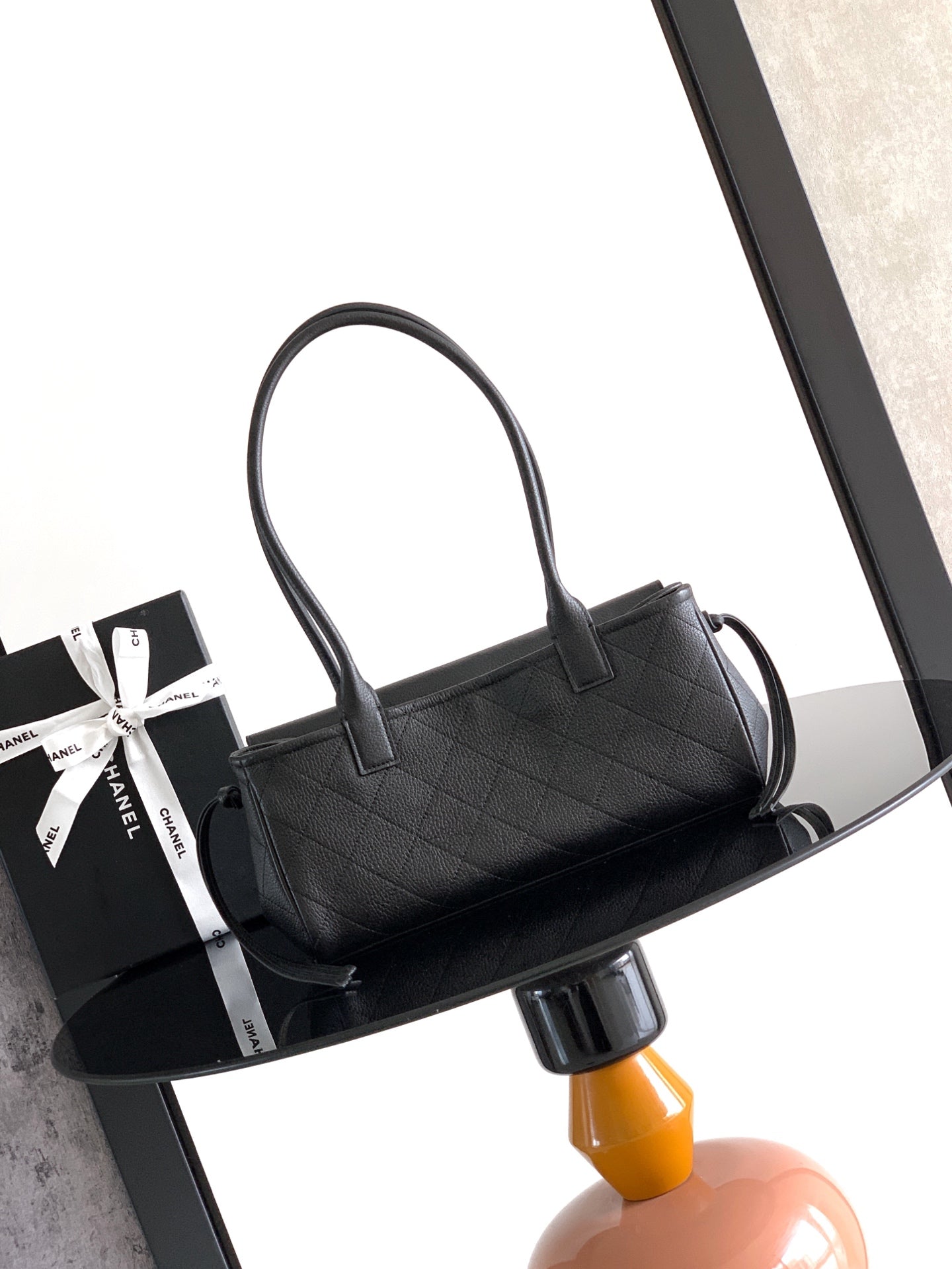 Black quilted leather handbag on side view with curved top handles