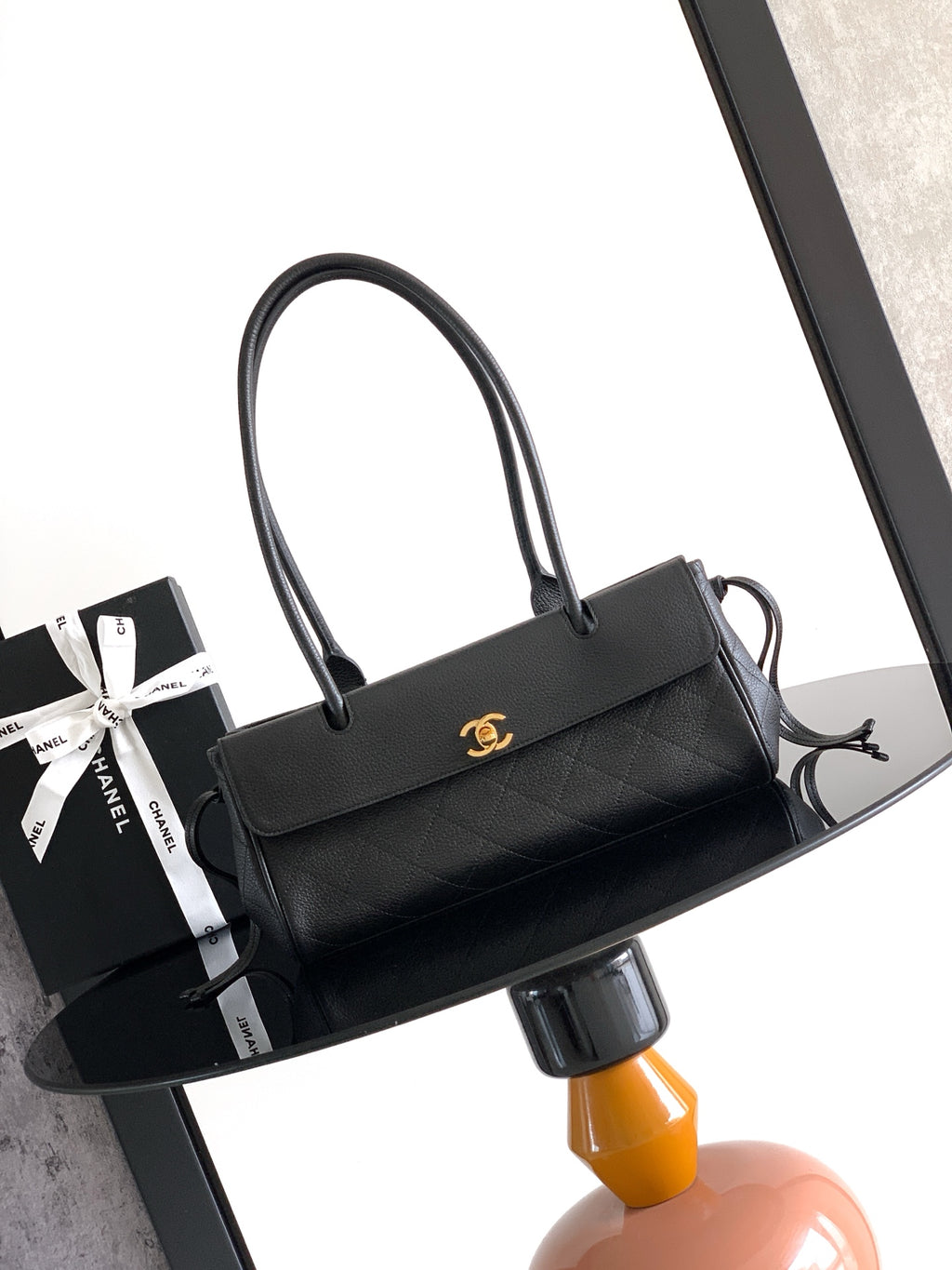 Black quilted leather handbag with top handles and gold Chanel CC clasp