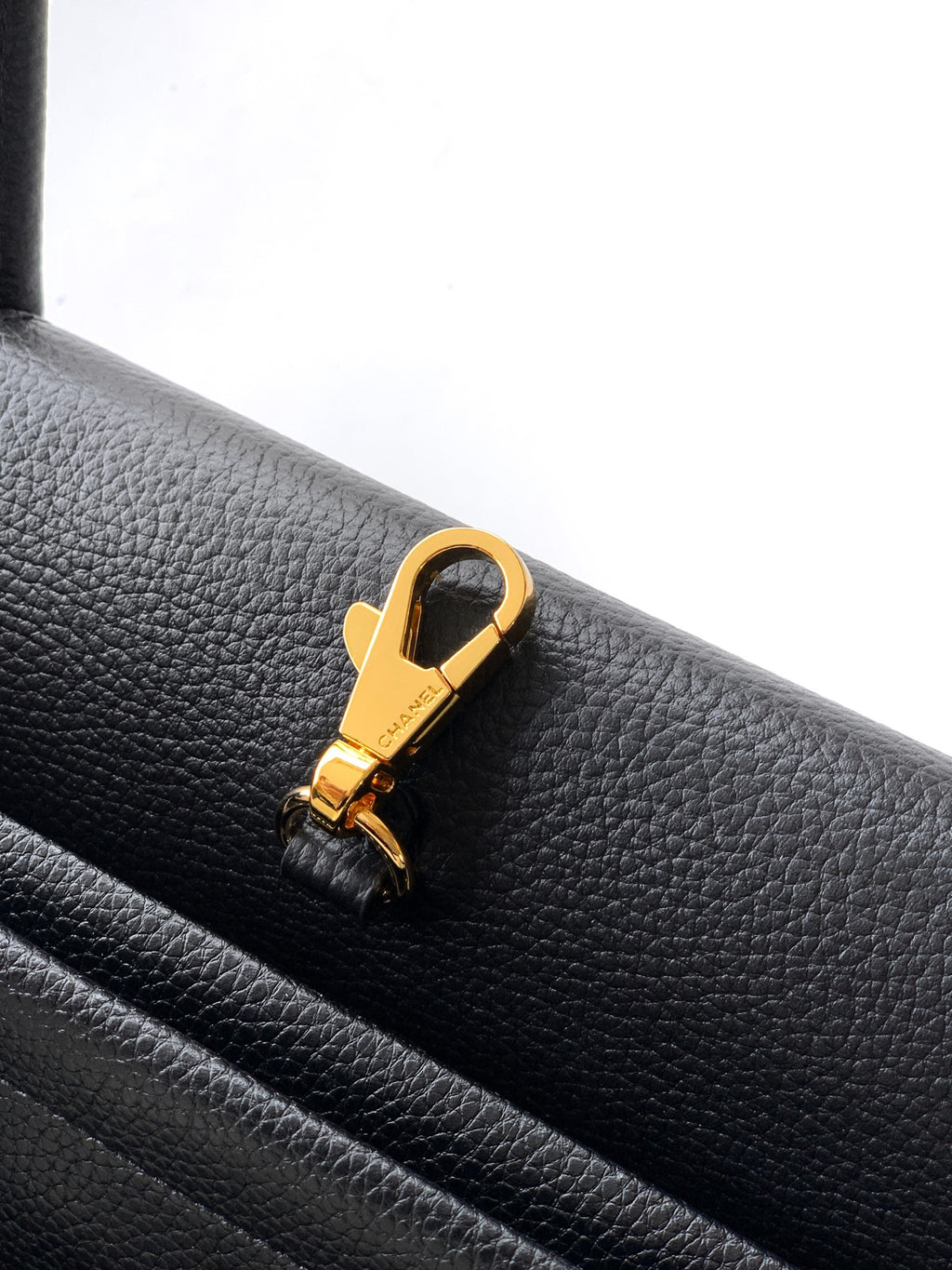 Black pebbled leather handbag with gold clasp and strap attachment ring