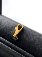 Black pebbled leather handbag with gold clasp and strap attachment ring