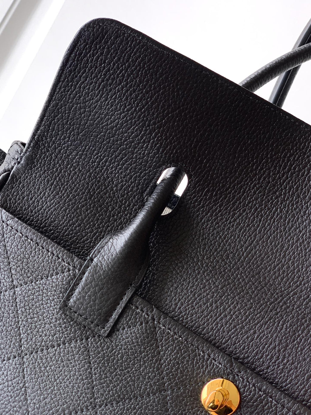 Black pebbled leather handbag with pocket detail and gold button hardware