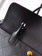 Black pebbled leather handbag with pocket detail and gold button hardware