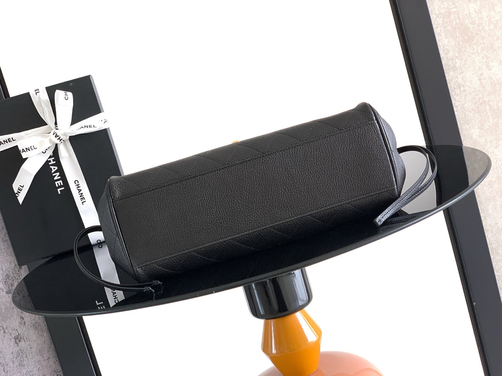 Black leather handbag, flat profile, top zipper and strap loops visible