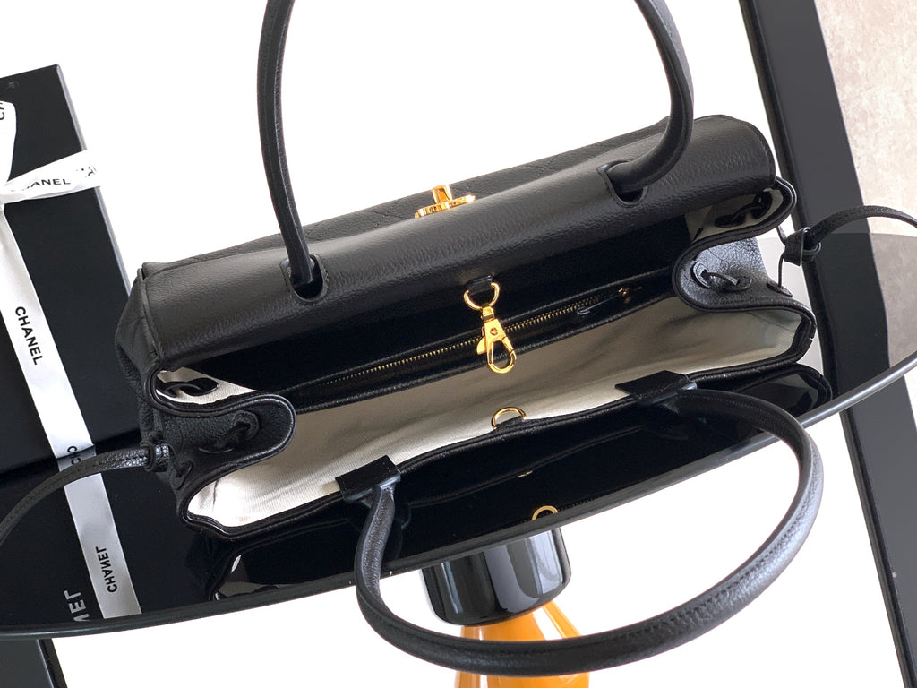 Black leather handbag opened to show interior lining and gold zipper pulls