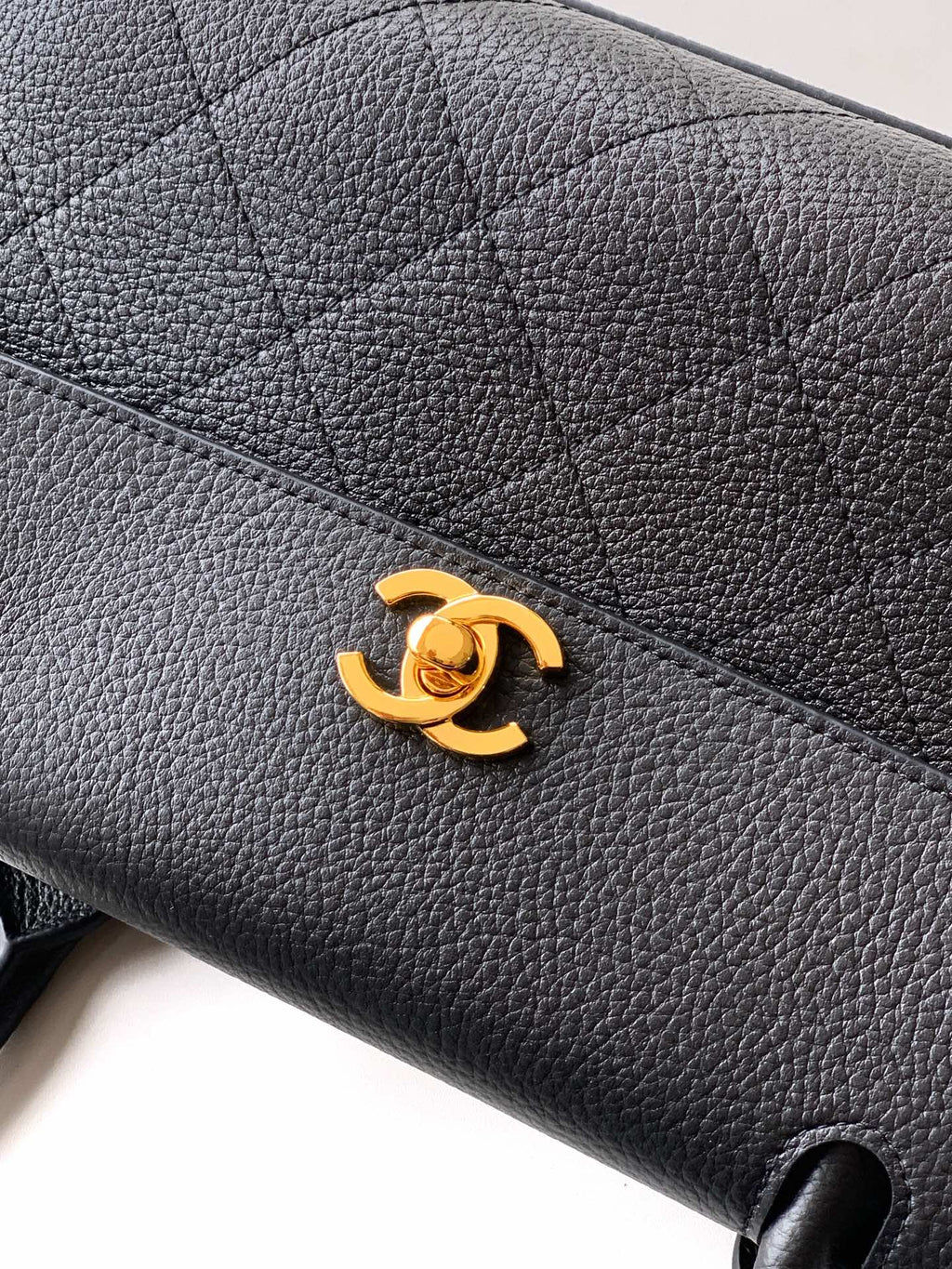 Black pebbled leather handbag with gold Chanel CC logo on front flap