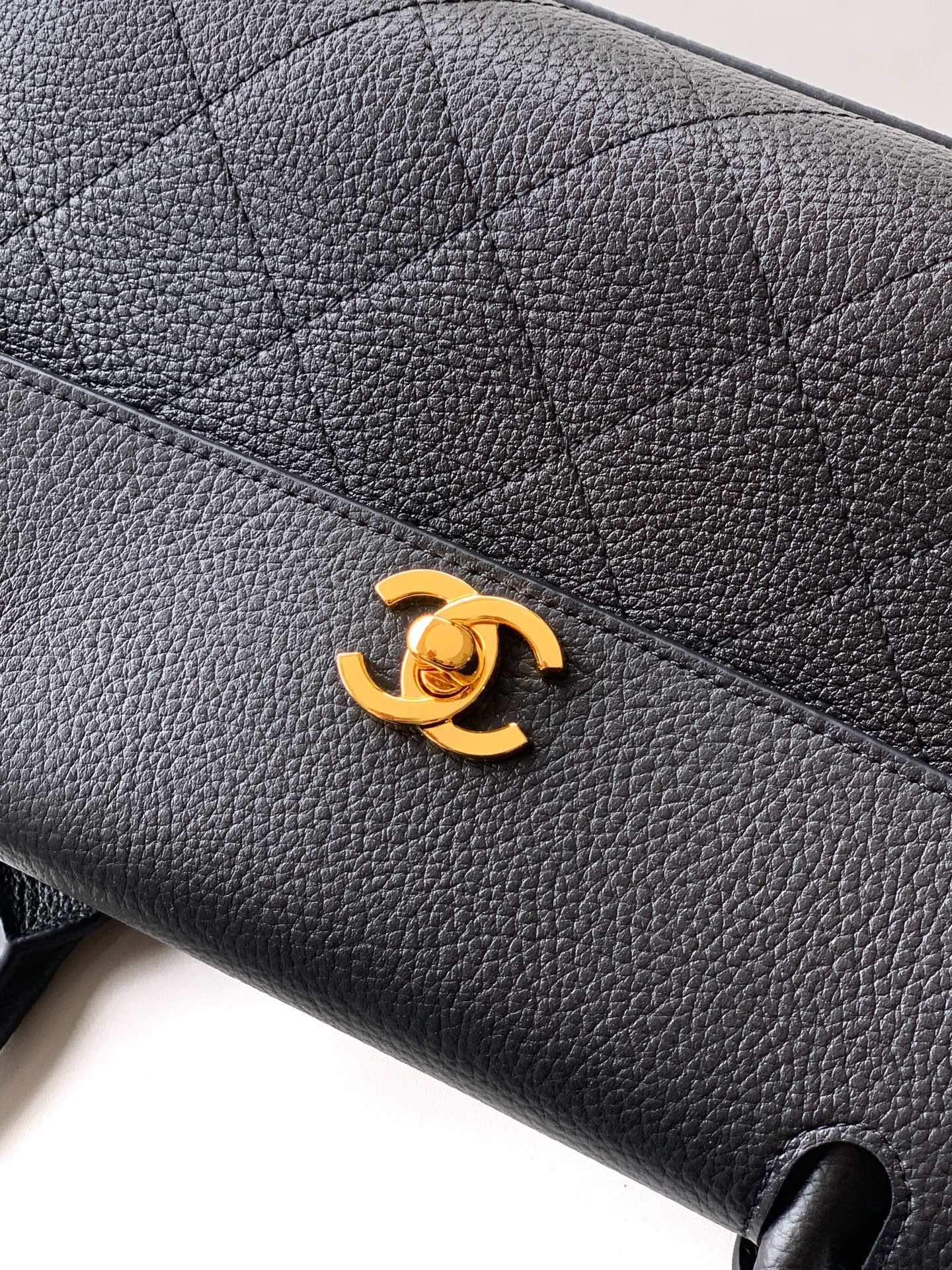 Black pebbled leather handbag with gold Chanel CC logo on front flap