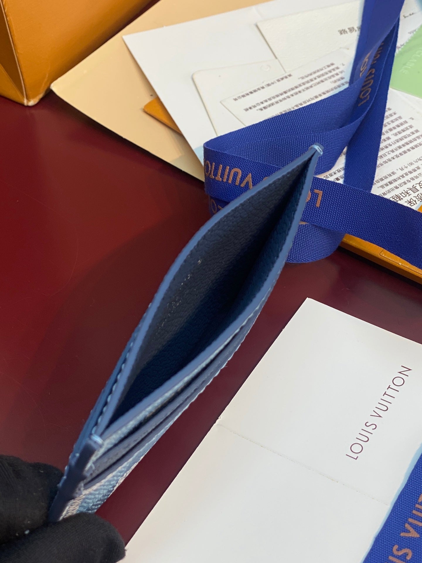 Blue checkered card holder shown from side with navy trim and zipper opening