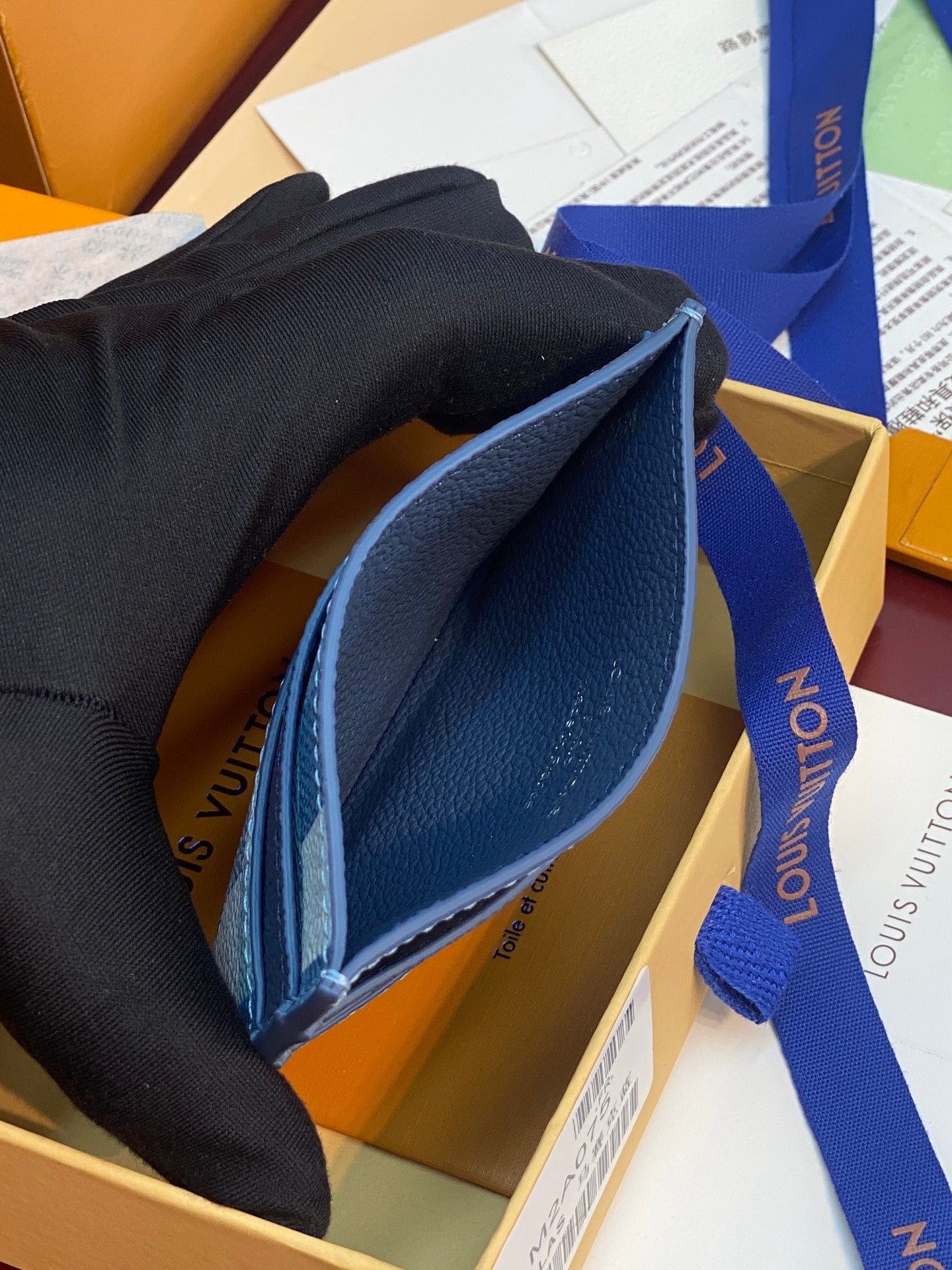 Louis Vuitton blue card holder opened, showing interior lining and navy trim