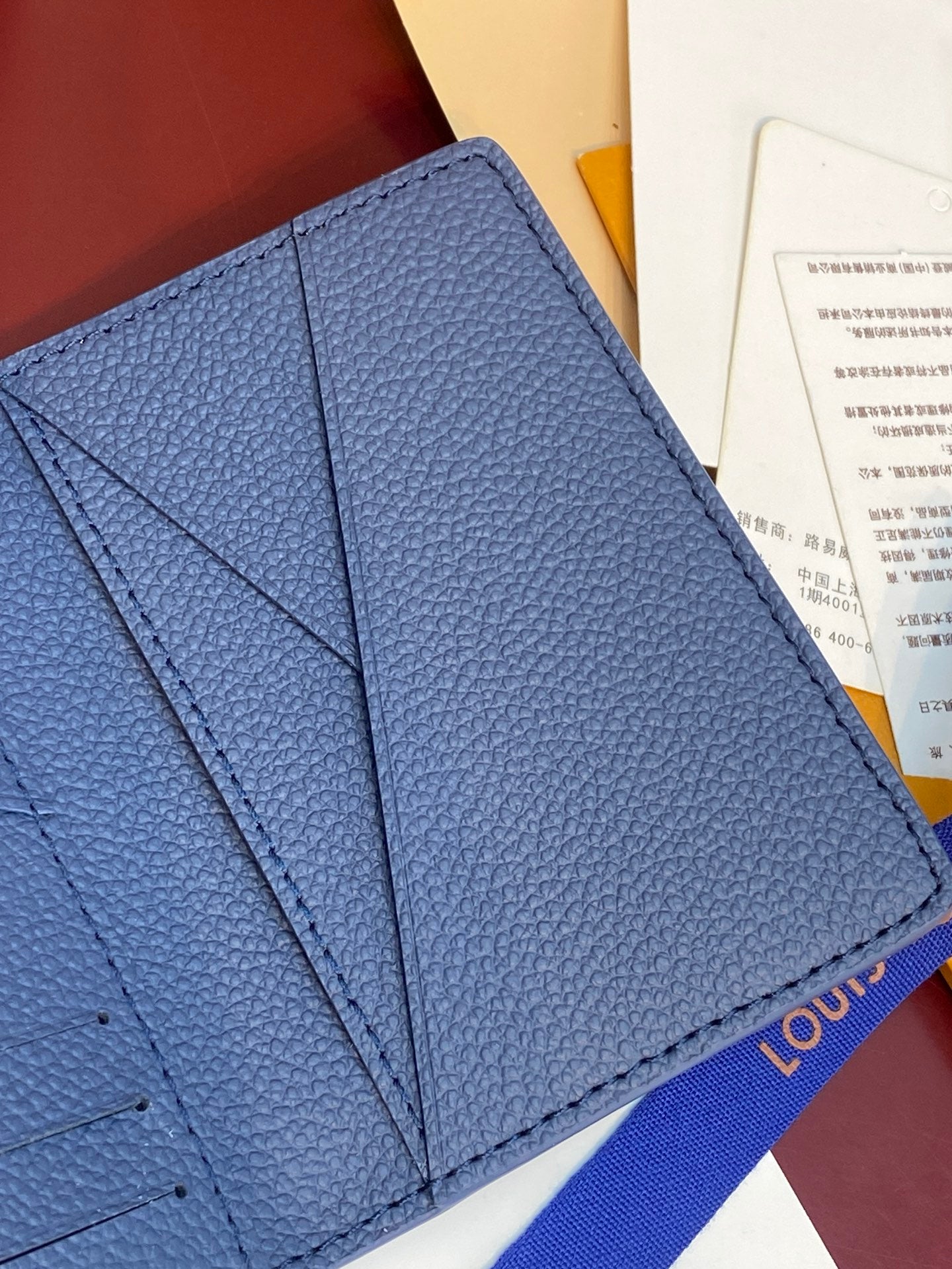 Blue leather card holder close-up showing inner pocket seams and stitching