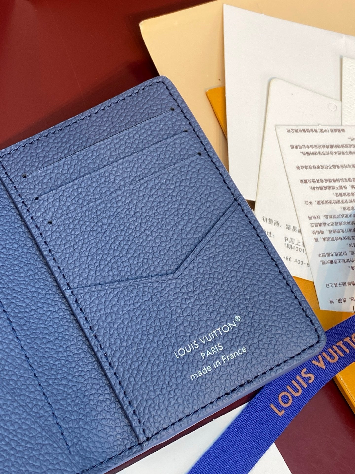 Blue textured leather card holder front with embossed logo and stitching