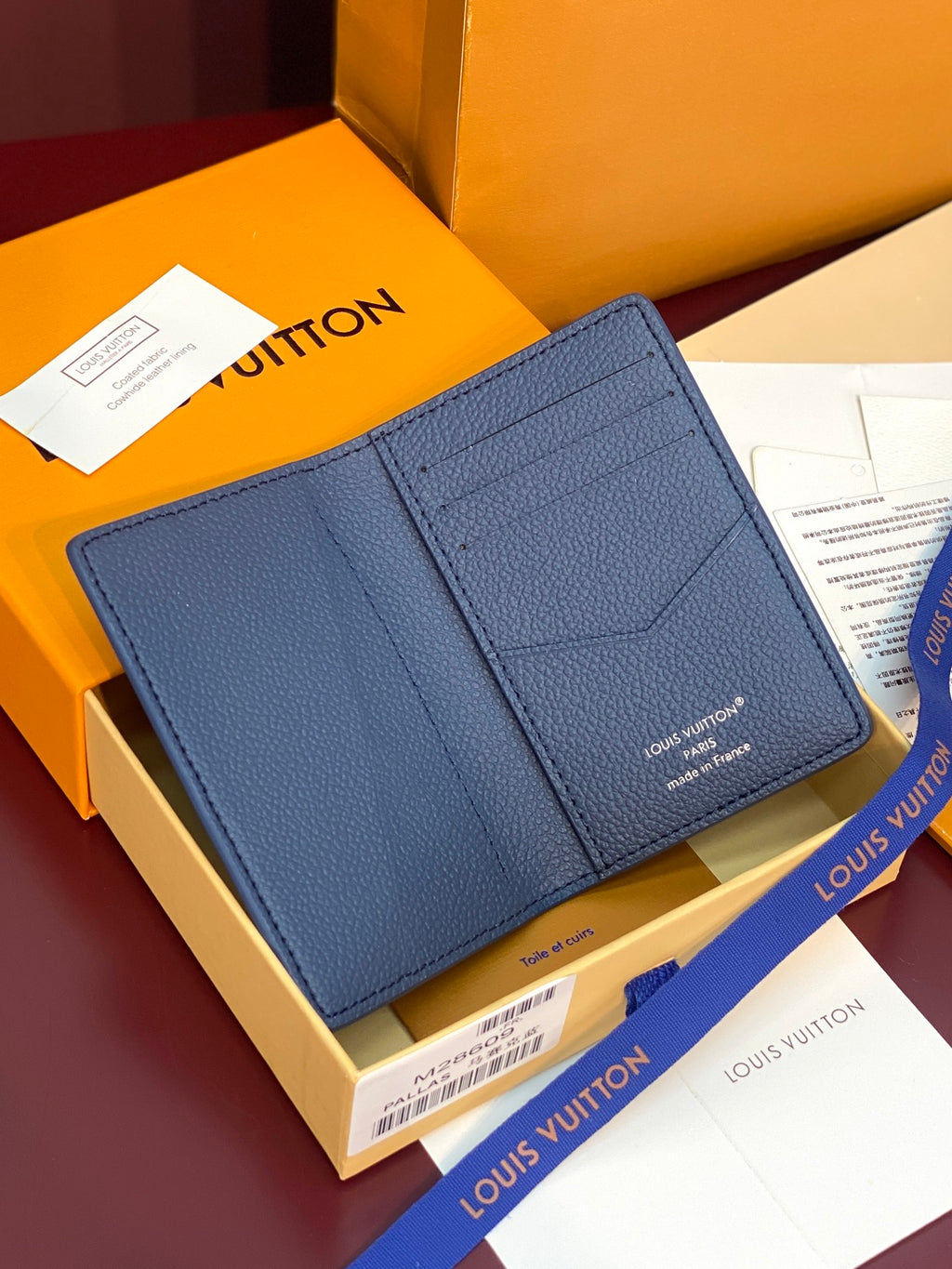 Blue textured leather card holder with front pocket and stitched edge