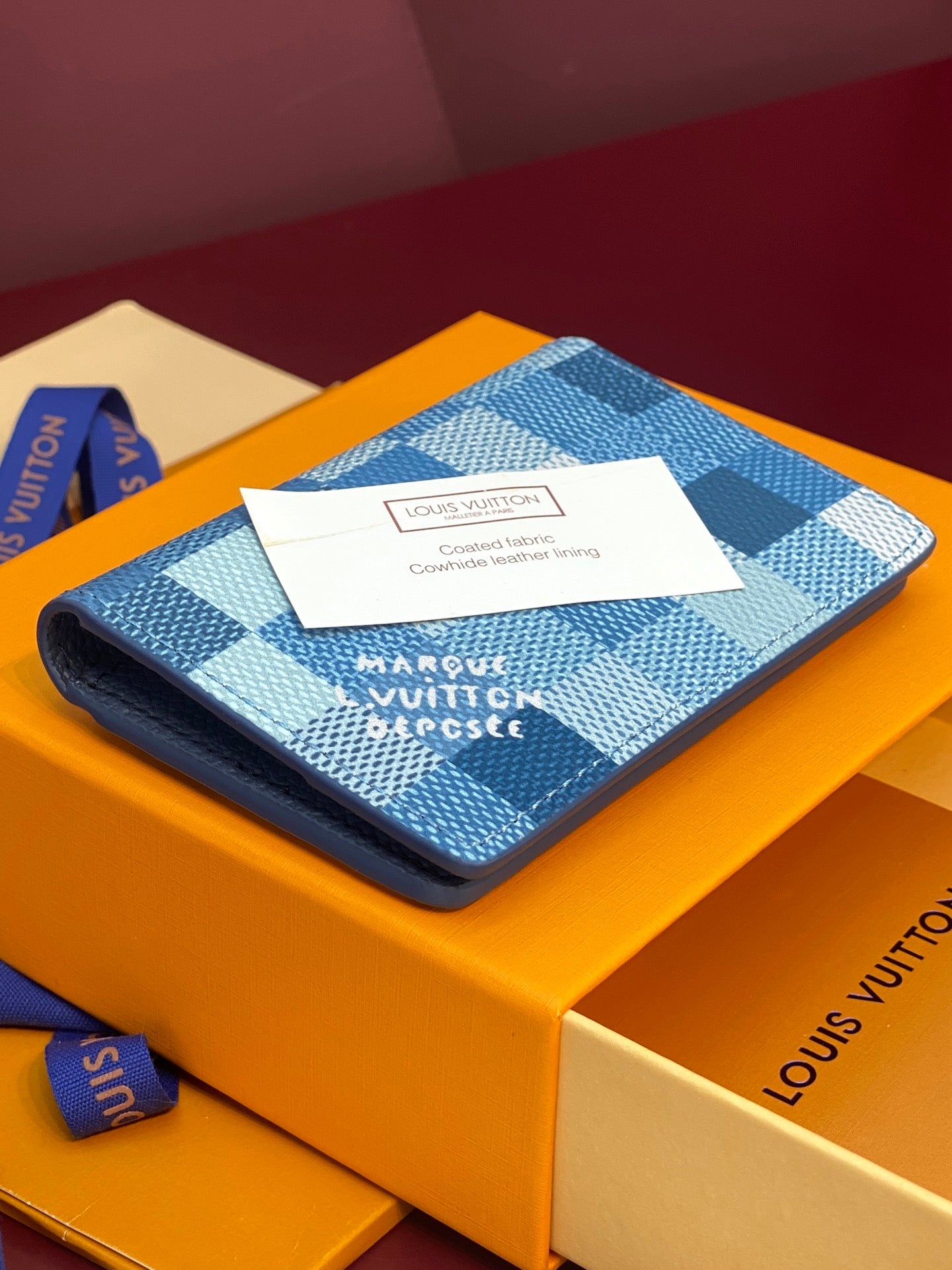 Blue checkered leather card holder with centered authenticity label