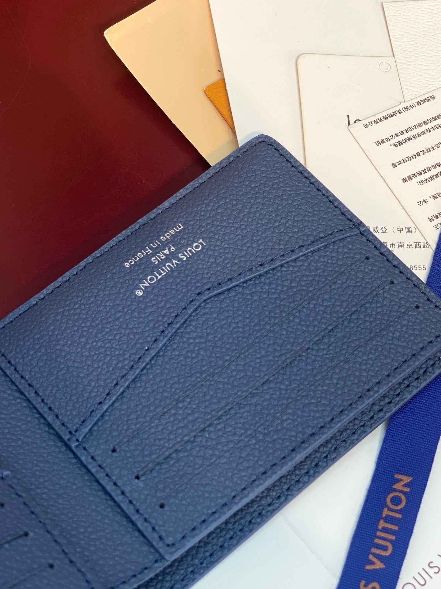 Louis Vuitton small wallet close-up, blue leather card slots with embossed logo