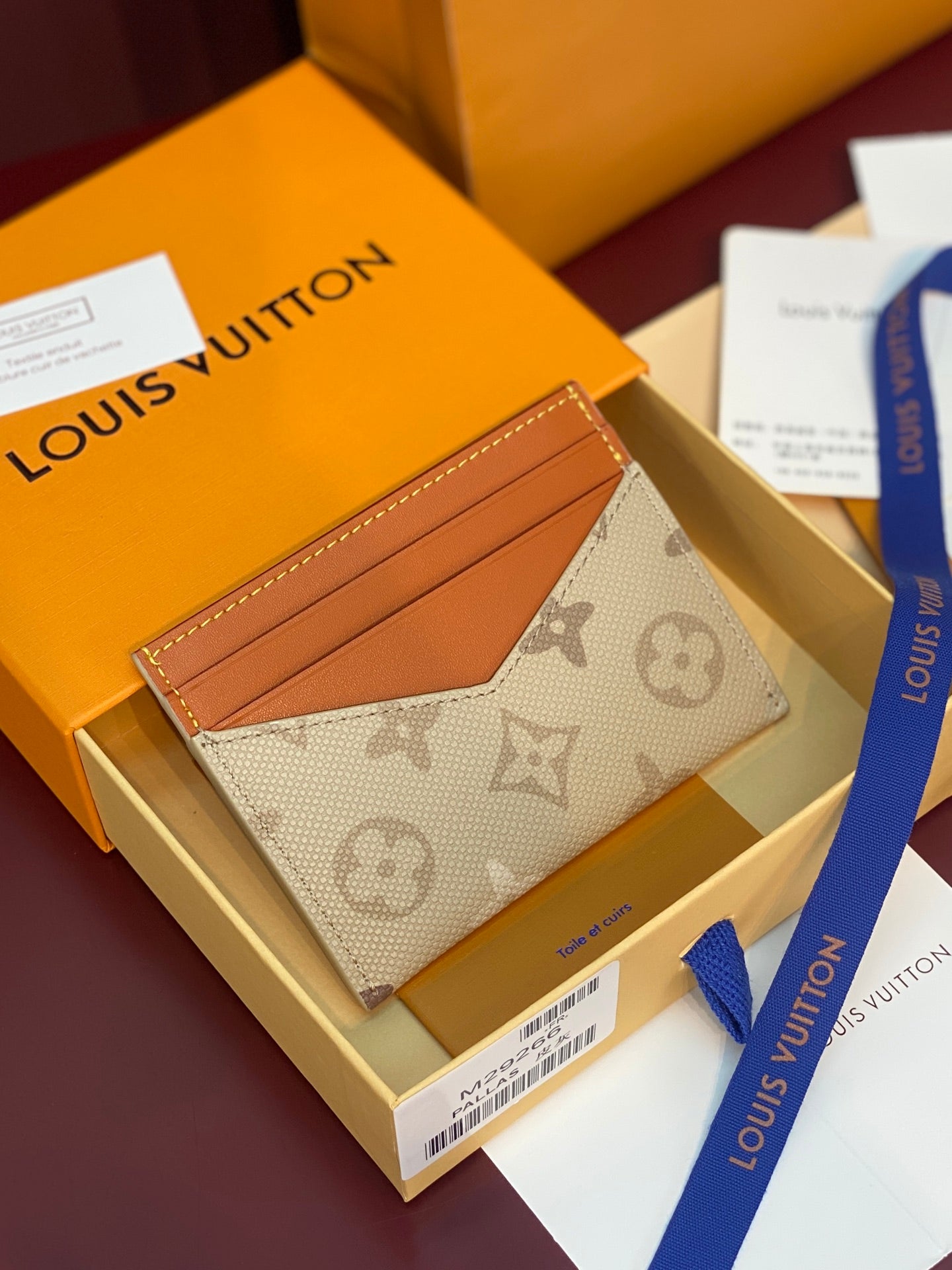 Louis Vuitton monogram card holder, beige canvas with tan pocket panel detail.