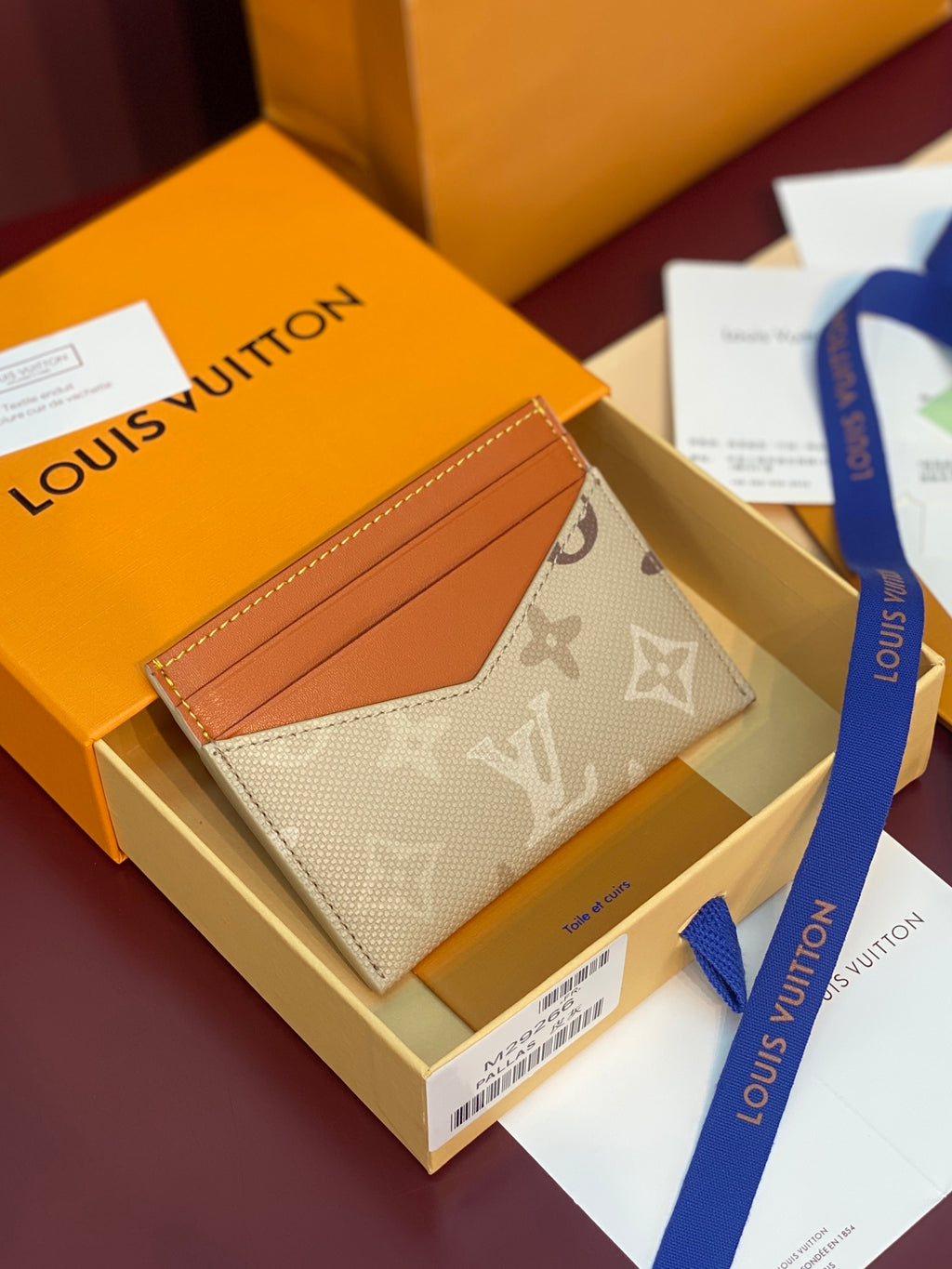Louis Vuitton monogram card holder with tan leather front and beige exterior.