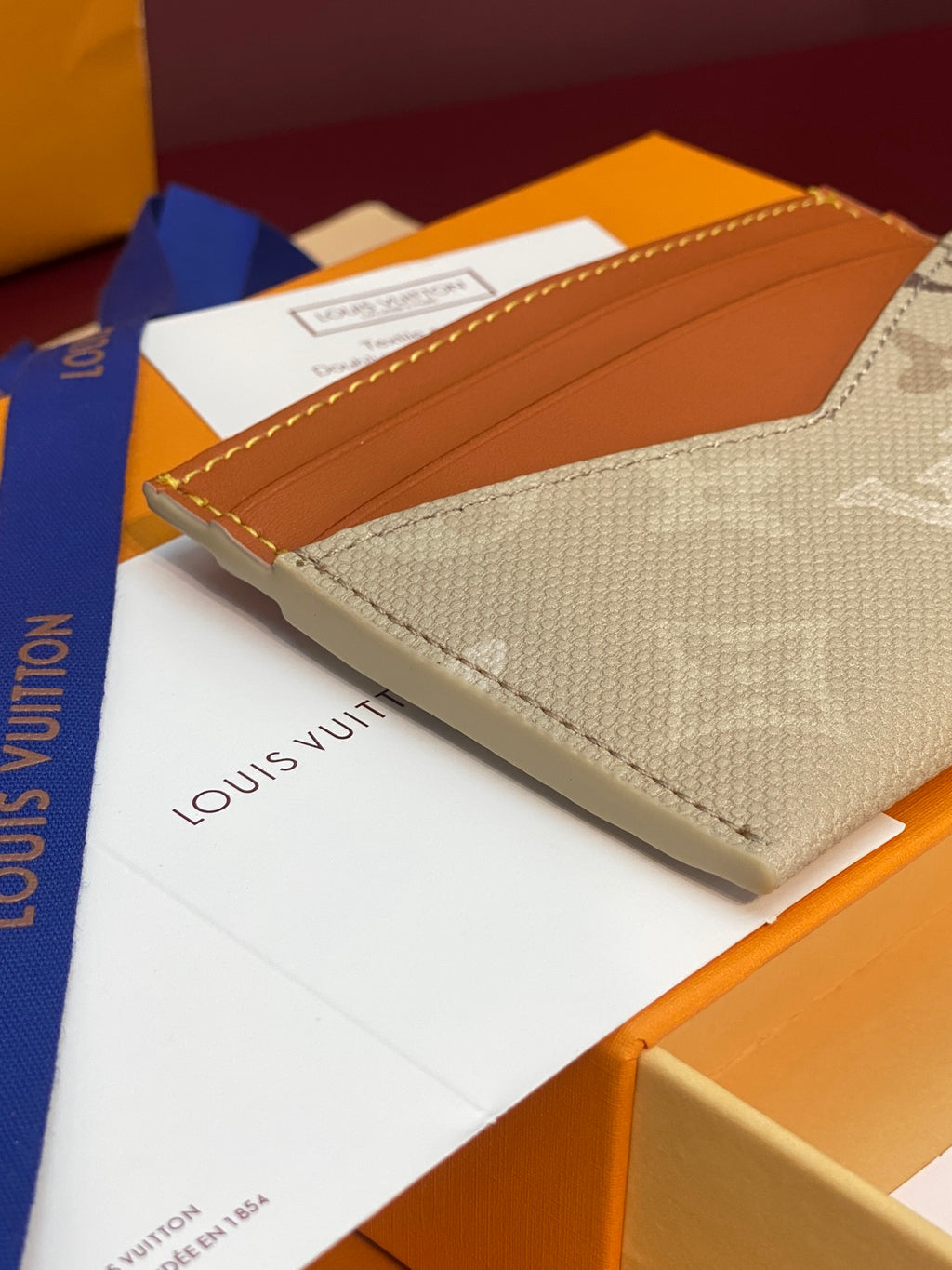 Louis Vuitton small card holder angled view with beige monogram canvas and tan leather top
