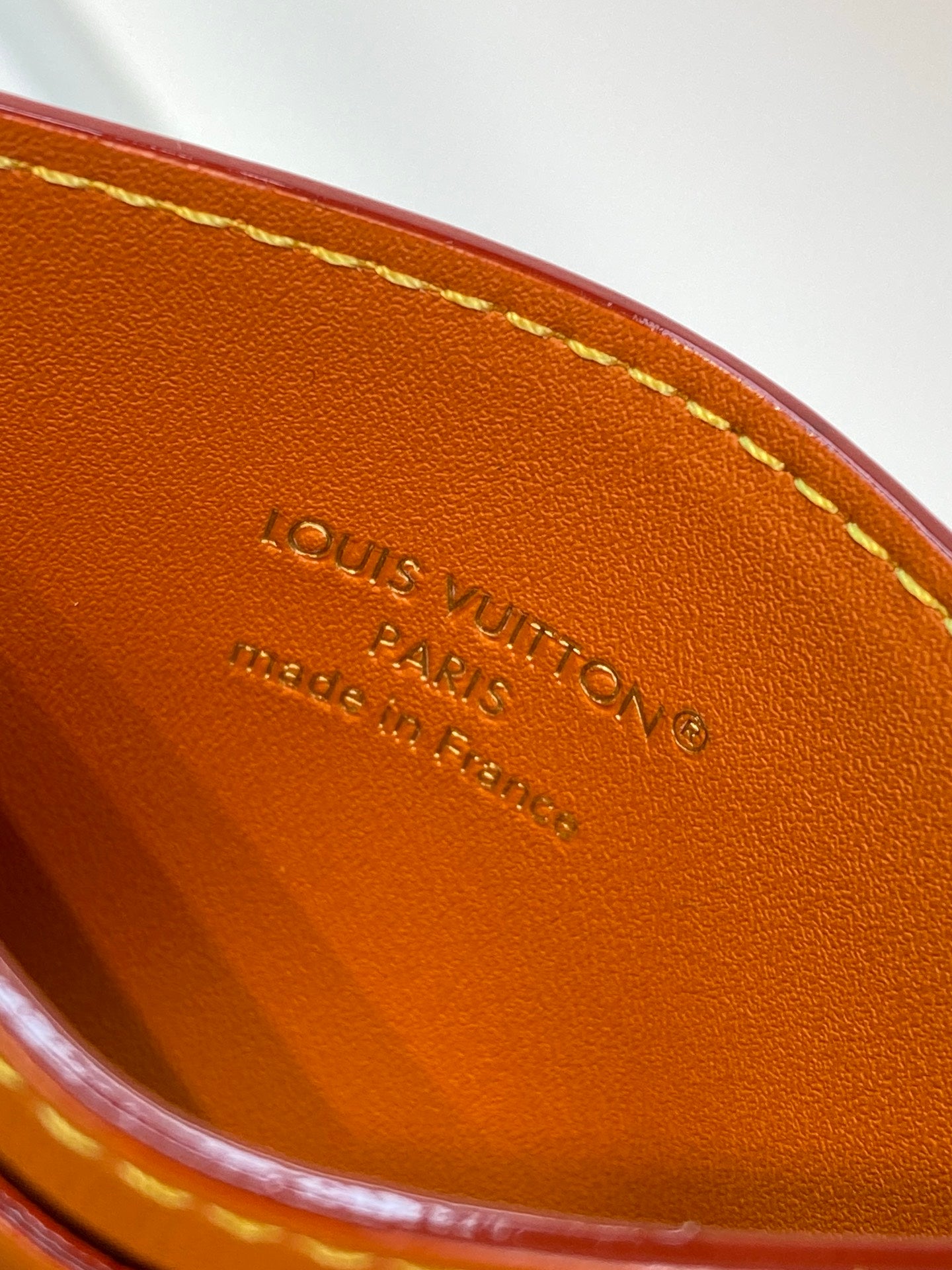 Louis Vuitton logo stamped on tan leather lining of a card holder.