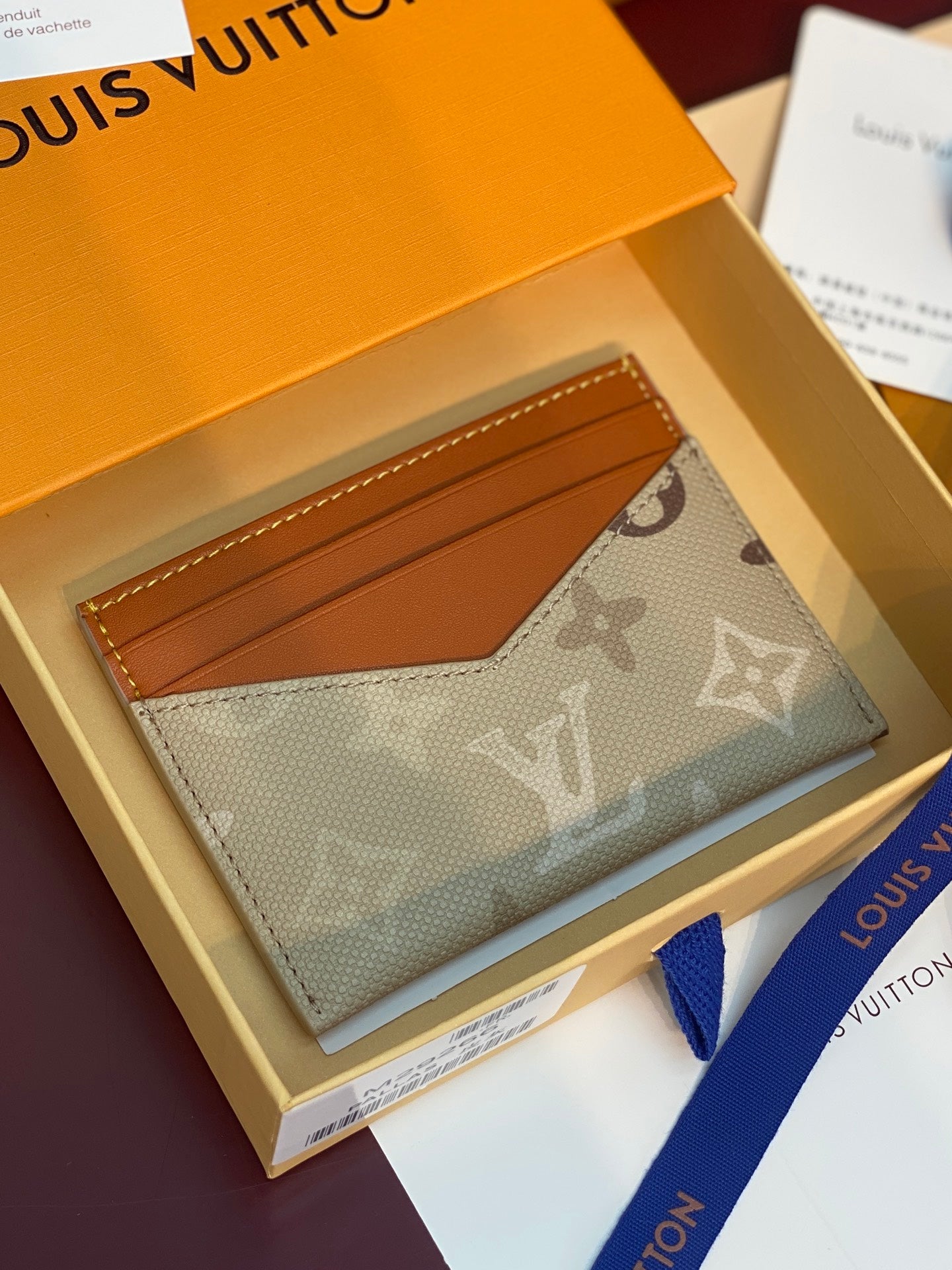 Louis Vuitton monogram card holder showing tan front pocket and beige monogram.