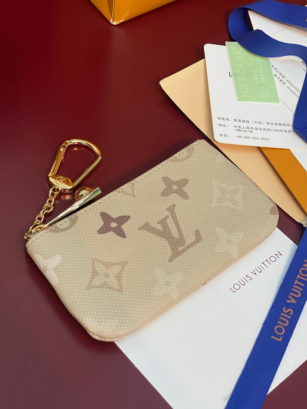 Beige monogram canvas wristlet pouch with gold-tone snap clasp and zipper