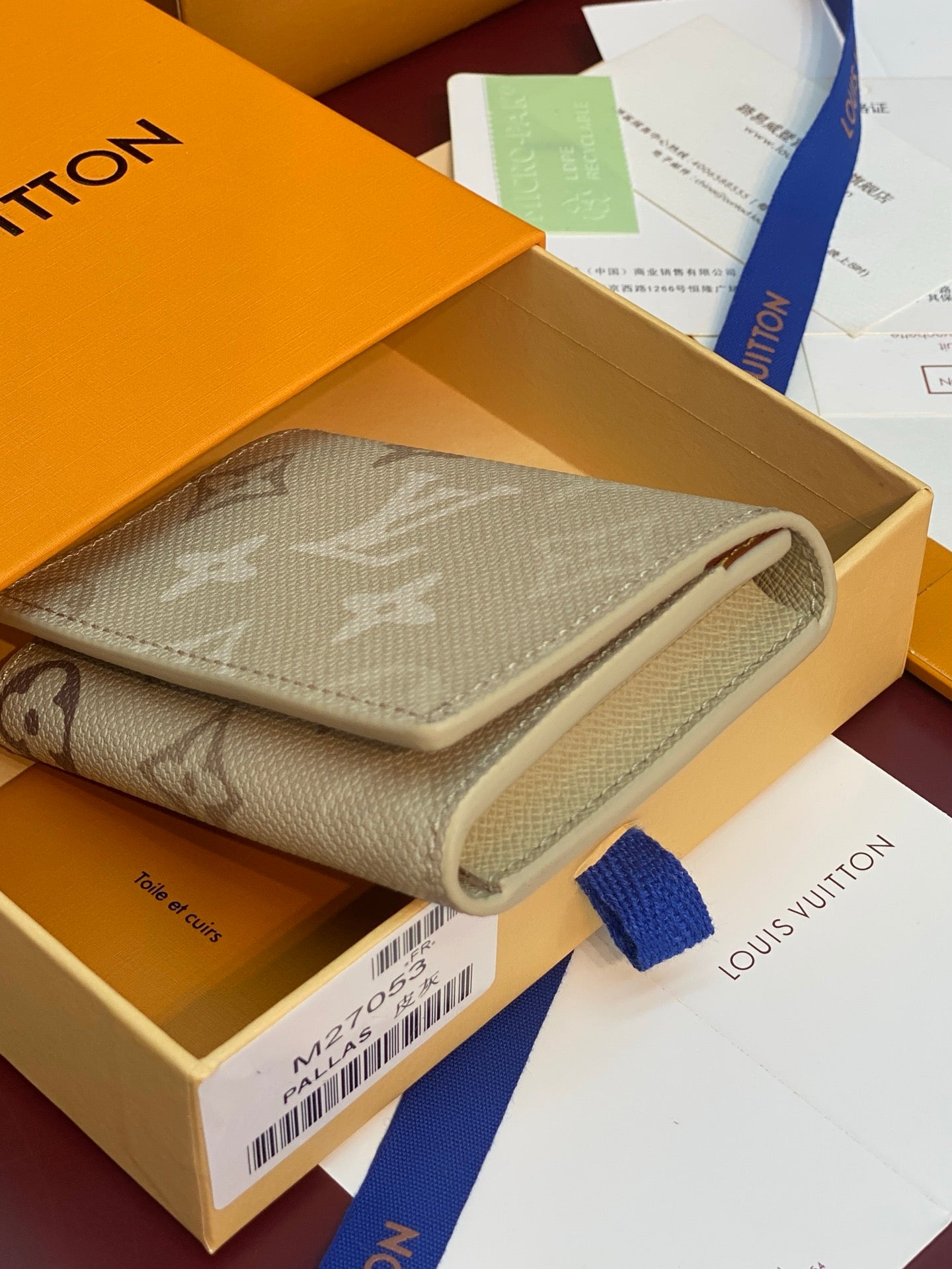 Beige Louis Vuitton monogram trifold wallet with snap closure and fabric strap