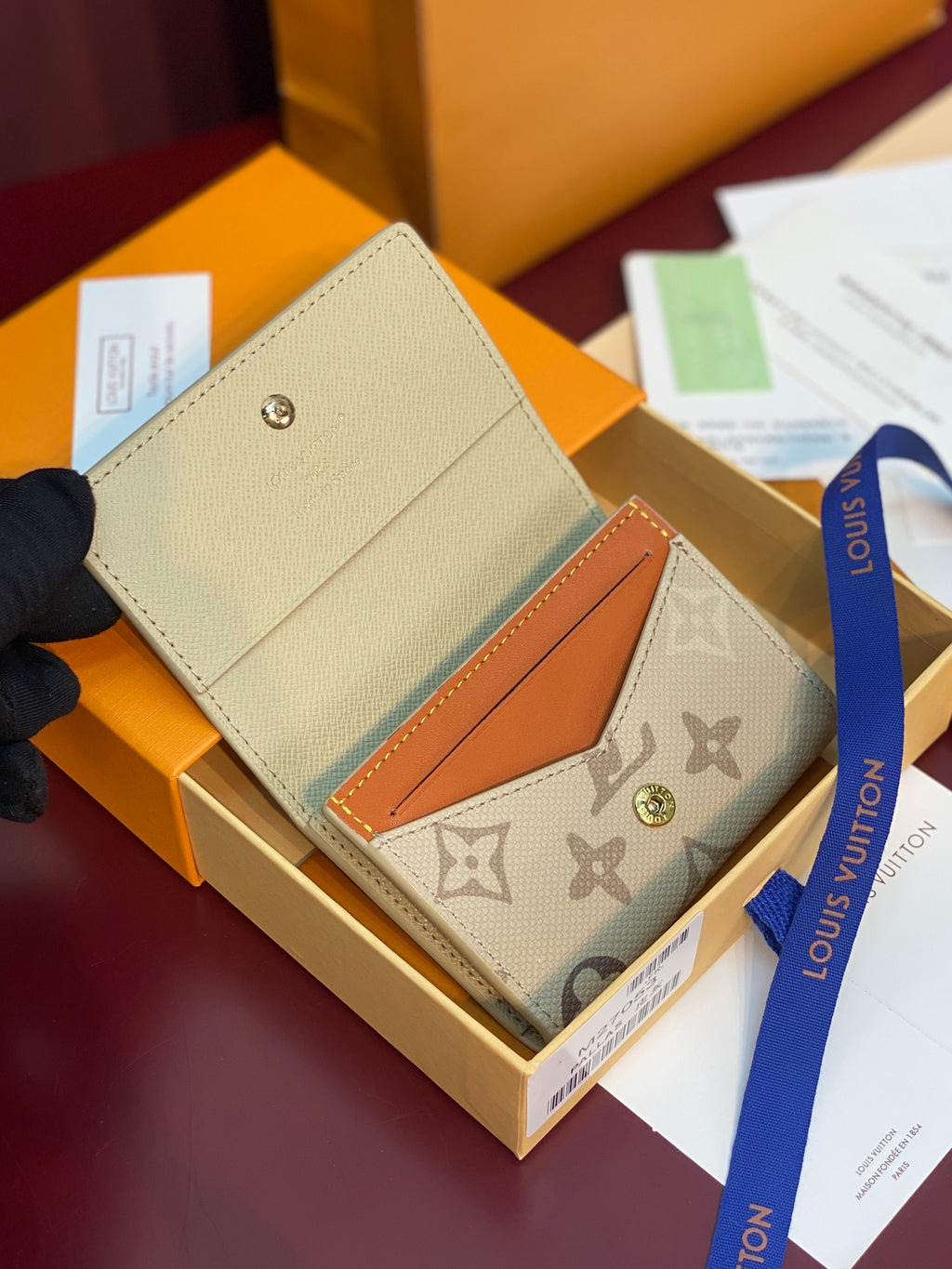 Beige Louis Vuitton monogram wallet with orange leather insert and gold snap
