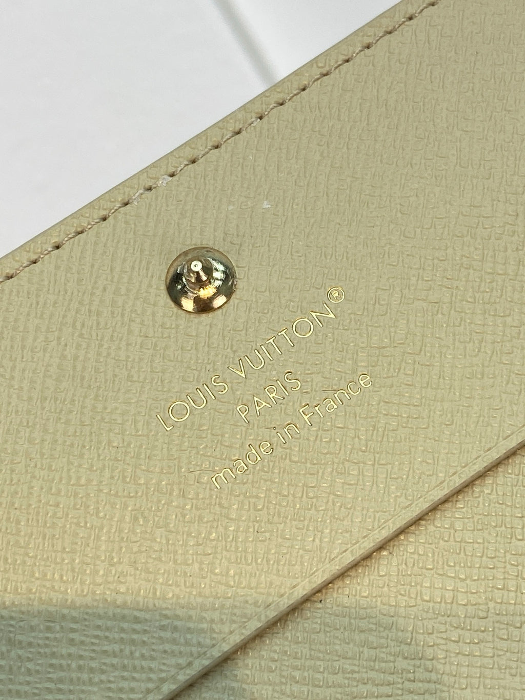 Beige Louis Vuitton monogram card holder with gold snap button and logo