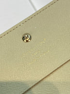 Beige Louis Vuitton monogram card holder with gold snap button and logo