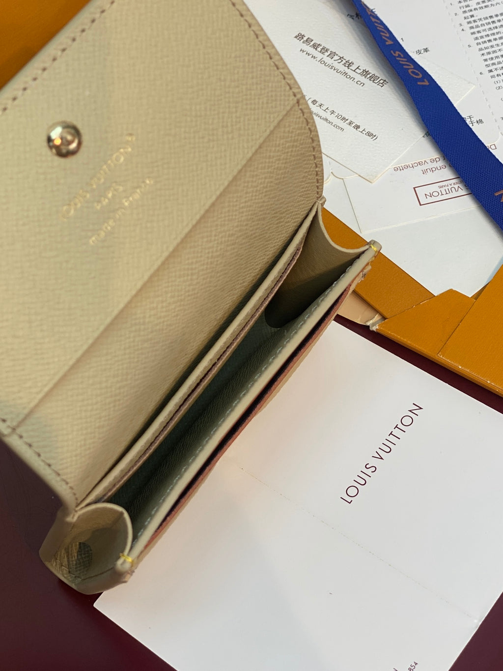 Open beige Louis Vuitton monogram card holder showing card slots and orange lining