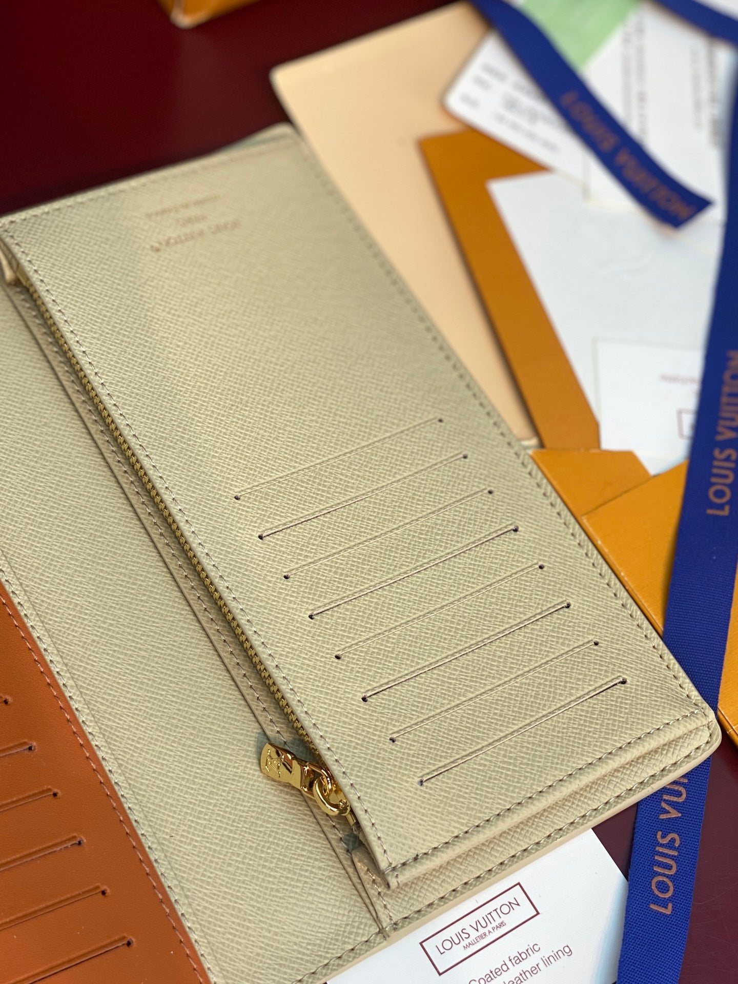 Light beige card wallet with central card slots and gold clasp hardware.