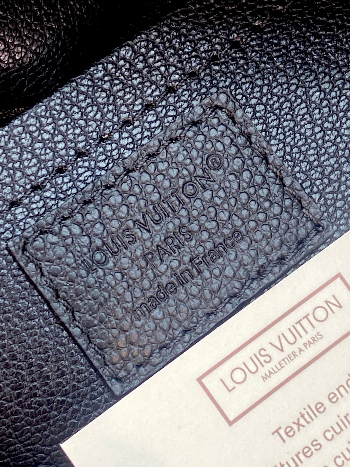 Louis Vuitton bag, dark textured leather interior panel with embossed brand markings