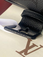 Louis Vuitton bag, dark textured leather close-up of strap buckle and stamped logo area