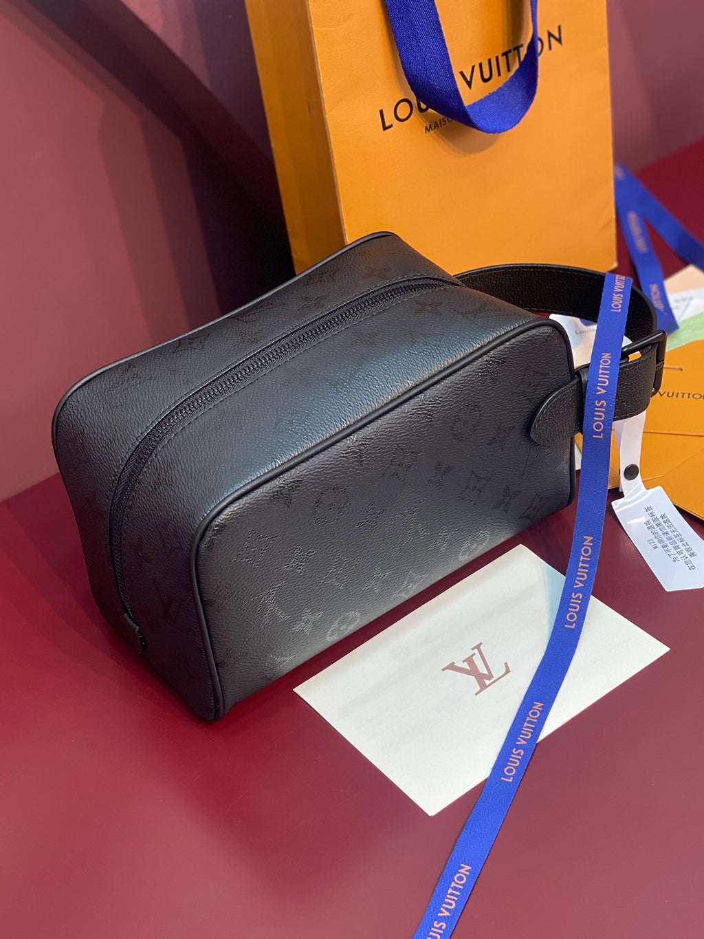Louis Vuitton bag, dark textured leather with rounded shape, zipper closure, and blue strap