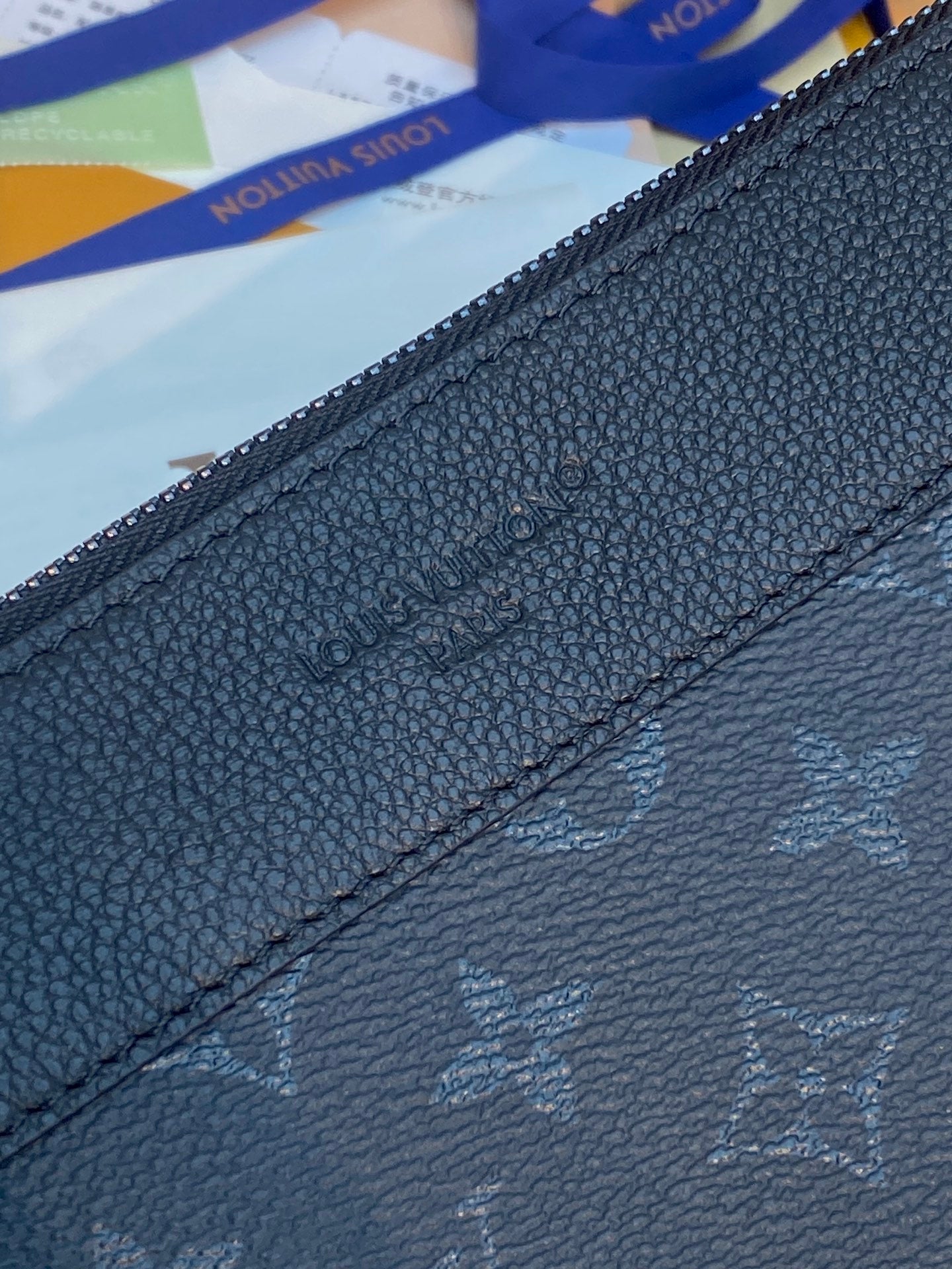 Louis Vuitton dark blue bag close-up showing zipper and embossed monogram texture