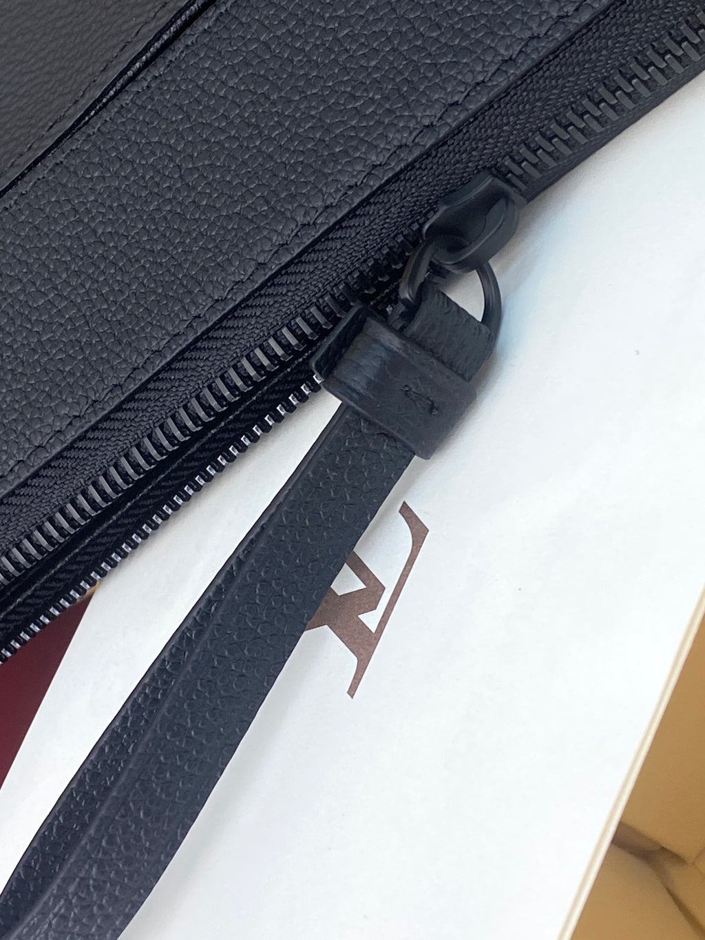 Close-up of Louis Vuitton zip track and dark blue fabric lining at the zipper pull