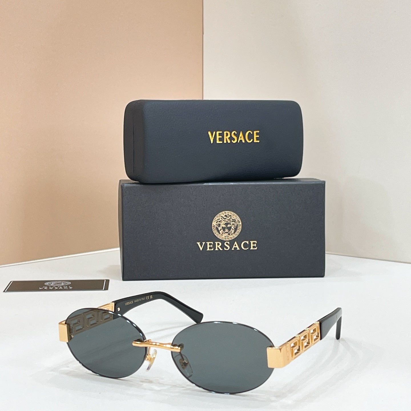 Designer sunglasses with dark blue lenses, black frame, and gold geometric temple detail