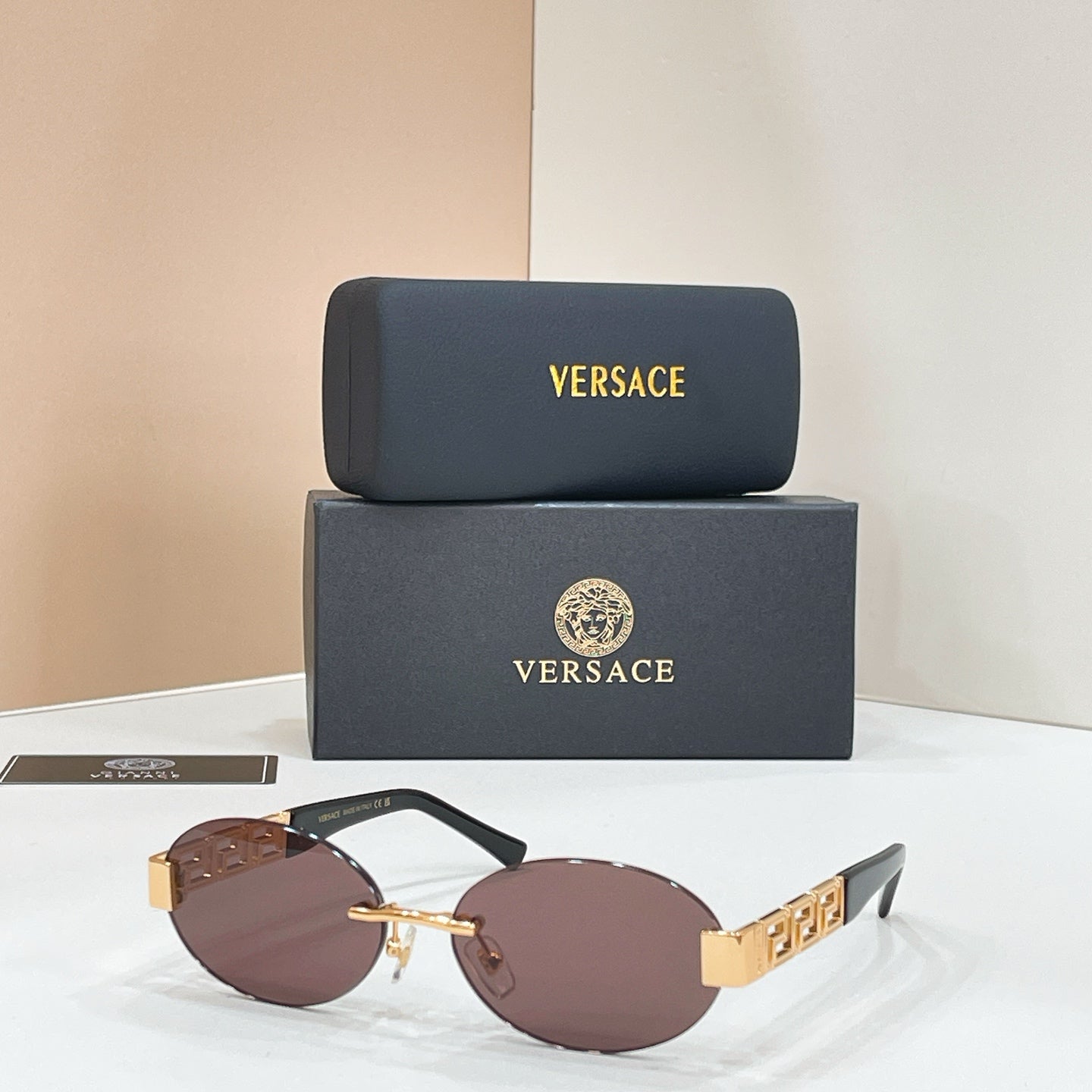 Versace round sunglasses with dark mauve lenses and gold logo temple hardware