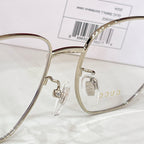 Gold-tone eyeglasses with clear lenses, logo hinge detail, and black temple arm