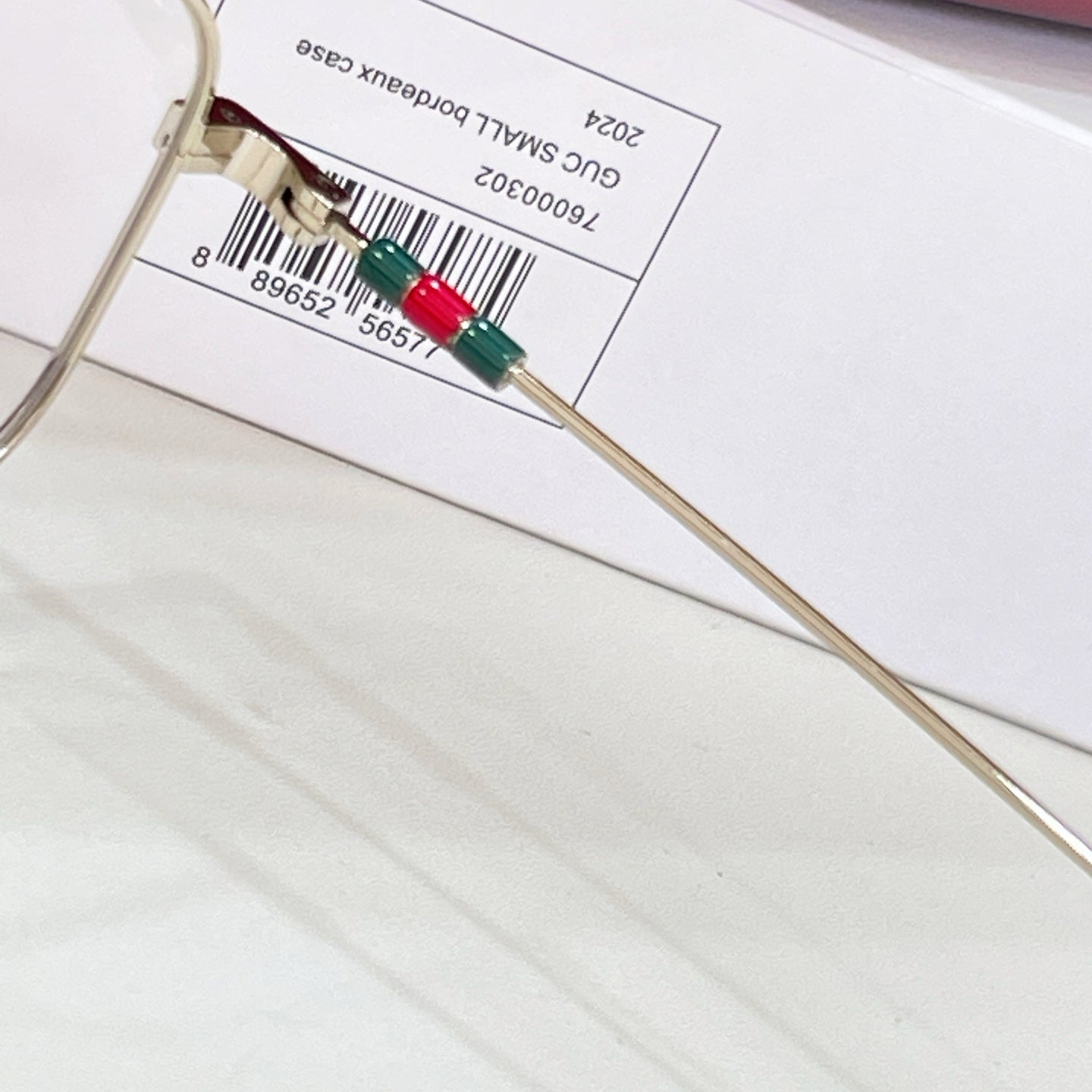 Gold-tone eyeglasses temple tip with green and red enamel accents