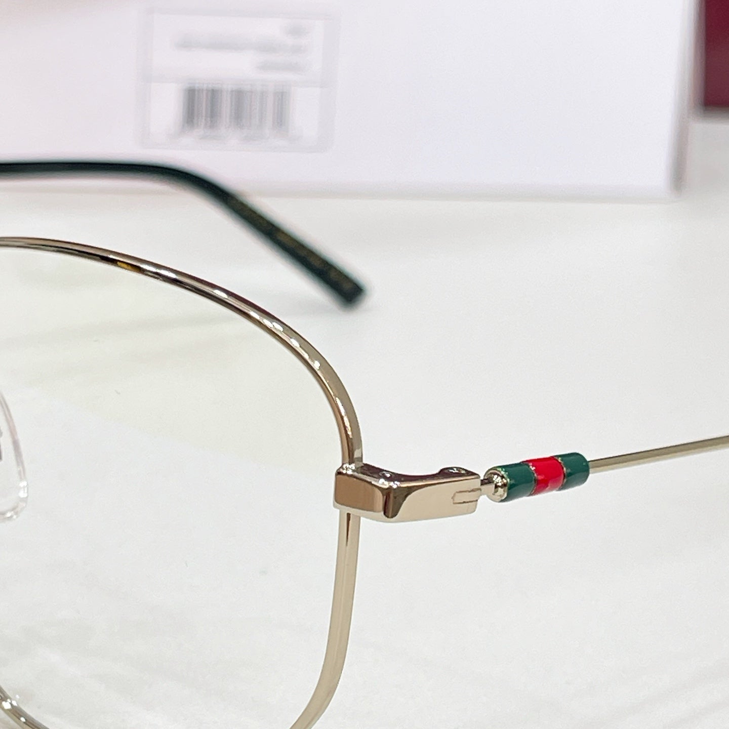 Gold-tone eyeglasses temple arm with black detailing and red-green enamel stripe