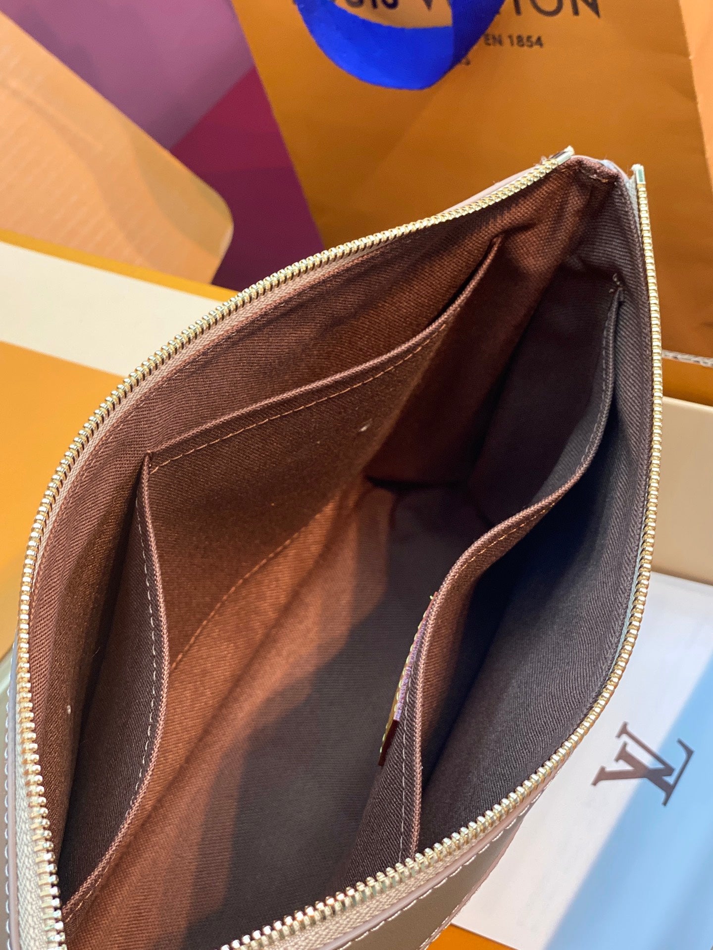 Small monogram pouch bag interior view, dark lining with gold zipper edge